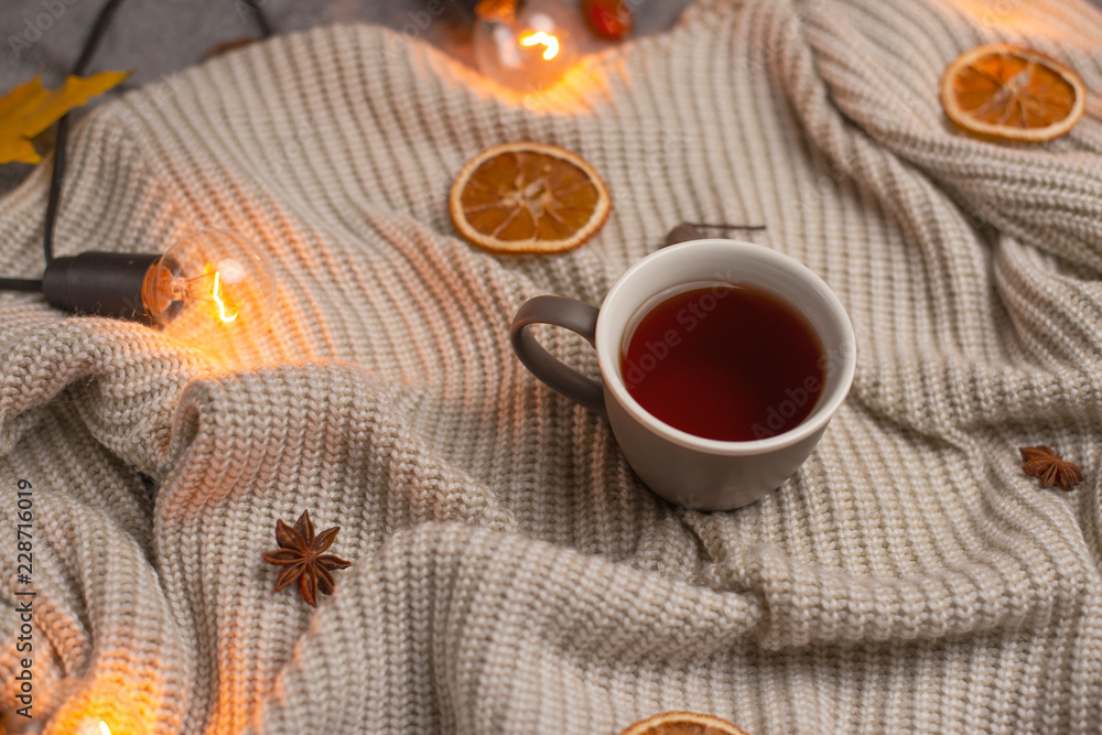 plaid with hot tea and a woolen blanket, autumn yellow leaves and white bulbs. Conception of warmth, comfort, comfort. View from above with empty space for an inscription