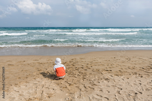 little boy on the beach playing with sand