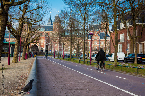 Cyclists at the bikeway next to the National Museum of Amsterdam in a cold early spring day