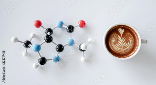 Coffee cup of cappuccino with latte art and molecule of caffeine structure on white table photo