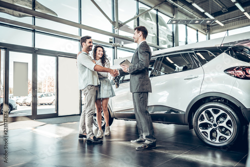 Young couple shaking hands with sales agent after a successful car buying photo