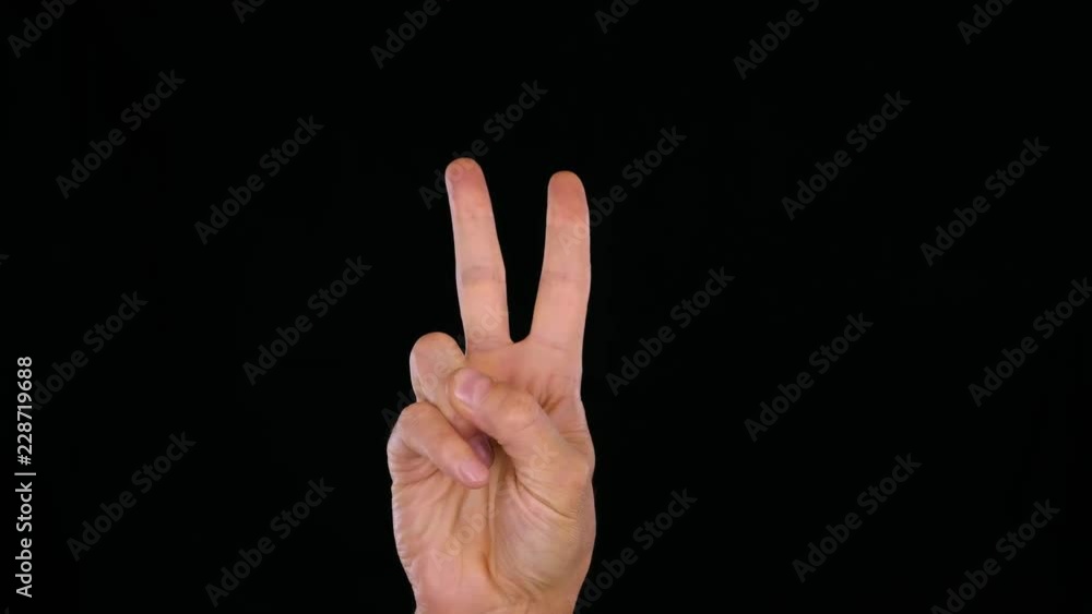 One male hand showing two fingers like quotes isolated on black background One male hand showing two fingers like quotes isolated on black background