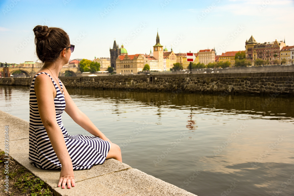 girl sitting on the waterfront with a view of prague