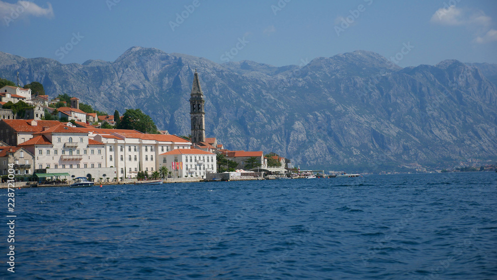 Picturesque view of the water of the Bay of Kotor and the church in the town of Perast. Historic buildings and beautiful wild nature attract many tourists and water sports enthusiasts here.