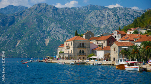 Picturesque view of the water of the Bay of Kotor and the church in the town of Perast. Historic buildings and beautiful wild nature attract many tourists and water sports enthusiasts here.