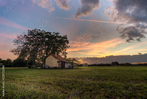 isoloated house in the field at sunset with cloudy sky photo