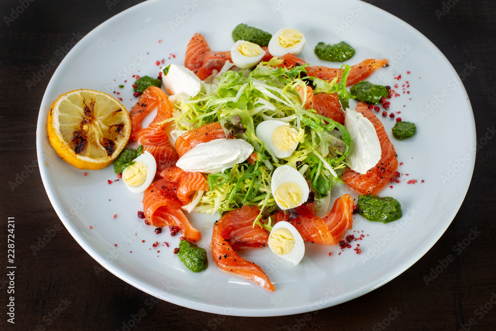 Salad from eggs, greens and trout. White plate.