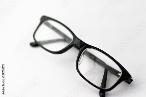 Pair of black glasses folded up on white background with free space
