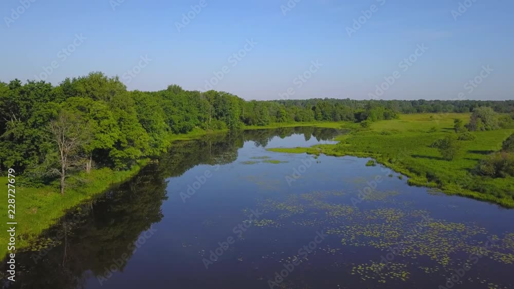 Flying over river and green meadow on Sunny summer day Flying over river and green meadow on Sunny summer day