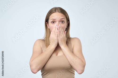 Surprised woman covering with hands her mouth
