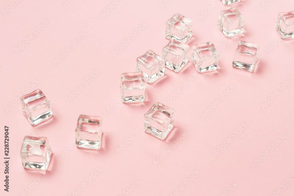 Ice cubes scattered on a light pink background. Flat lay, top vi Ice cubes scattered on a light pink background. Flat lay, top vi