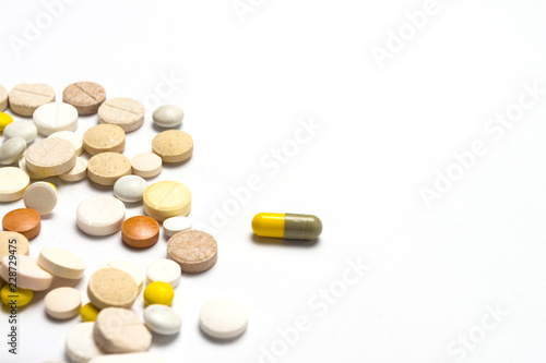 Pills of different sizes and colors and on a white isolated back