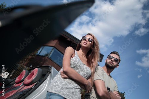 bottom view.beautiful couple standing near a convertible car