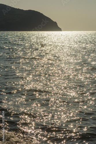 Teifstehende Sonne vom Meer refelktiert vor Hügel photo