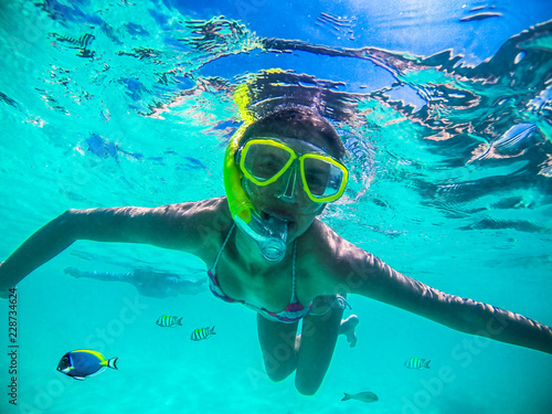 Young woman snorkeling in the tropical Oliveli island , Maldives.