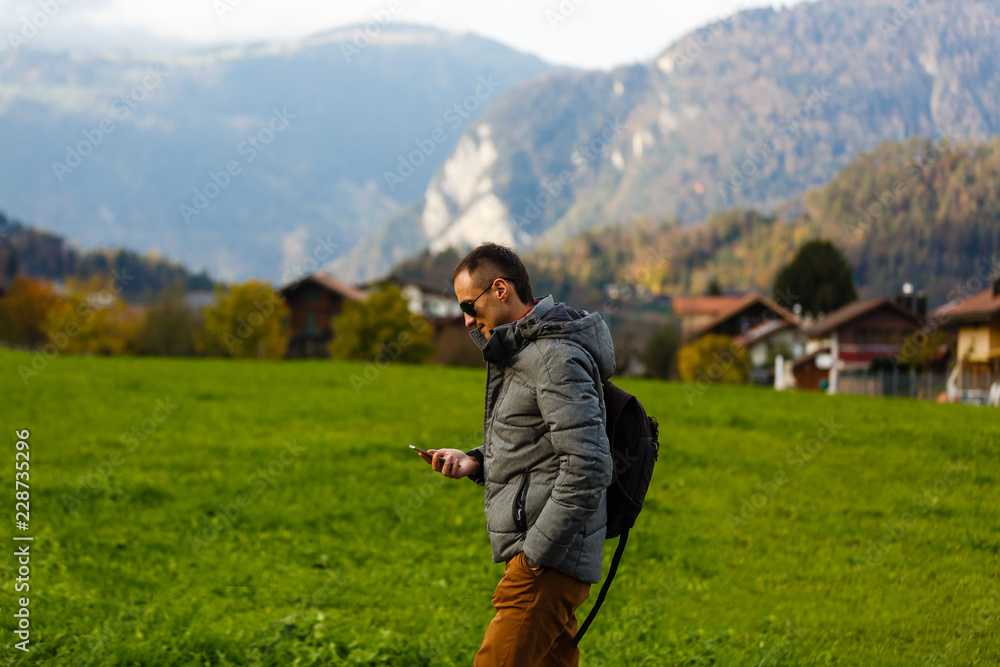 A man turist with a gadget walking on a rural path in Swiss Alps