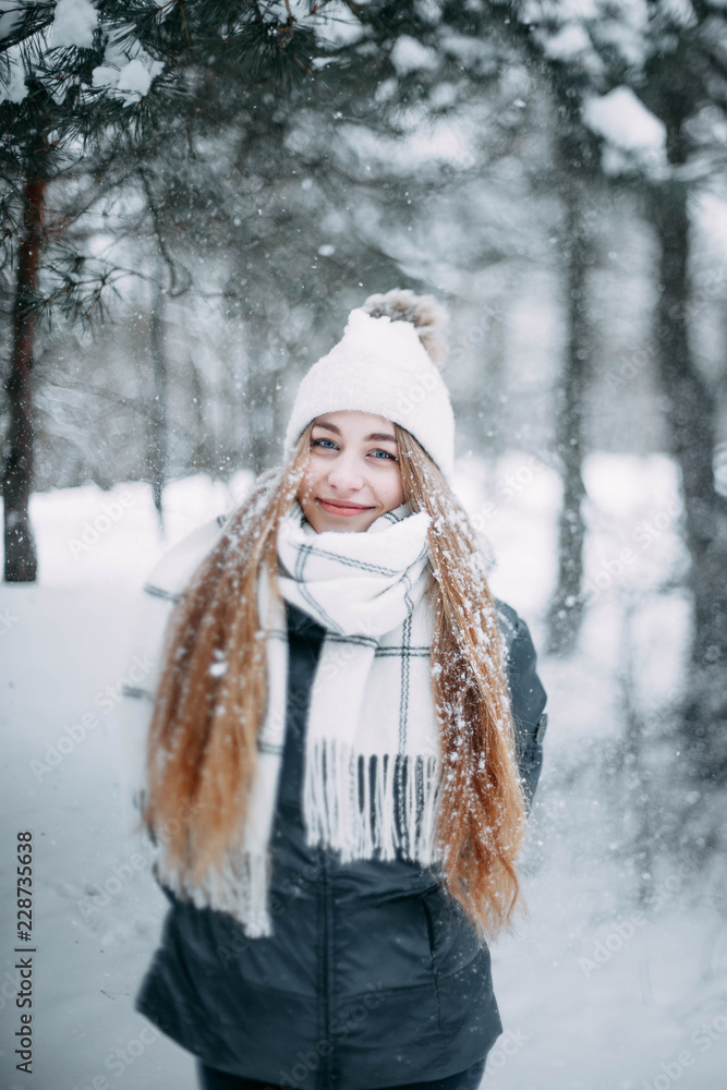 young blonde girl in a winter snow-covered forest in a knitted hat. young blonde girl in a winter snow-covered forest in a knitted hat.