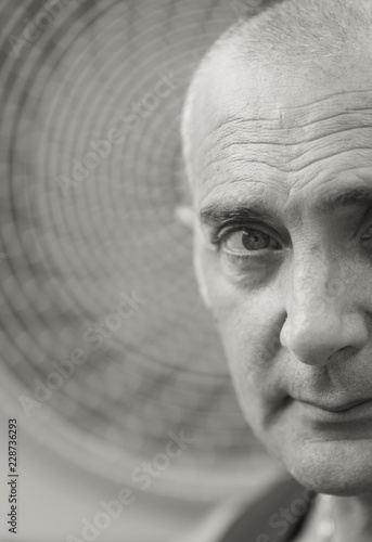 A man is posing with naked torso and vest. A wheel of a fan coil is on the background. photo