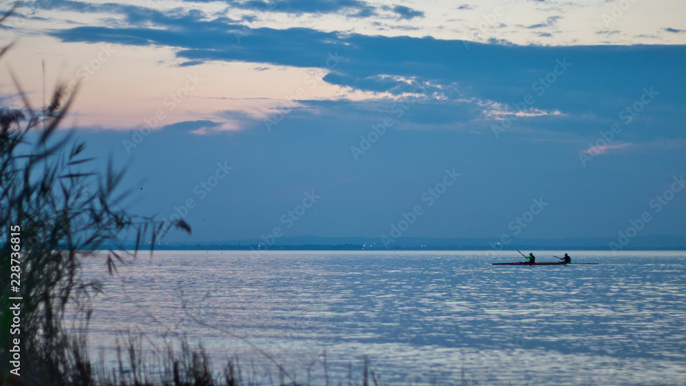 Kanufahrer auf See bei Sonnenuntergang
