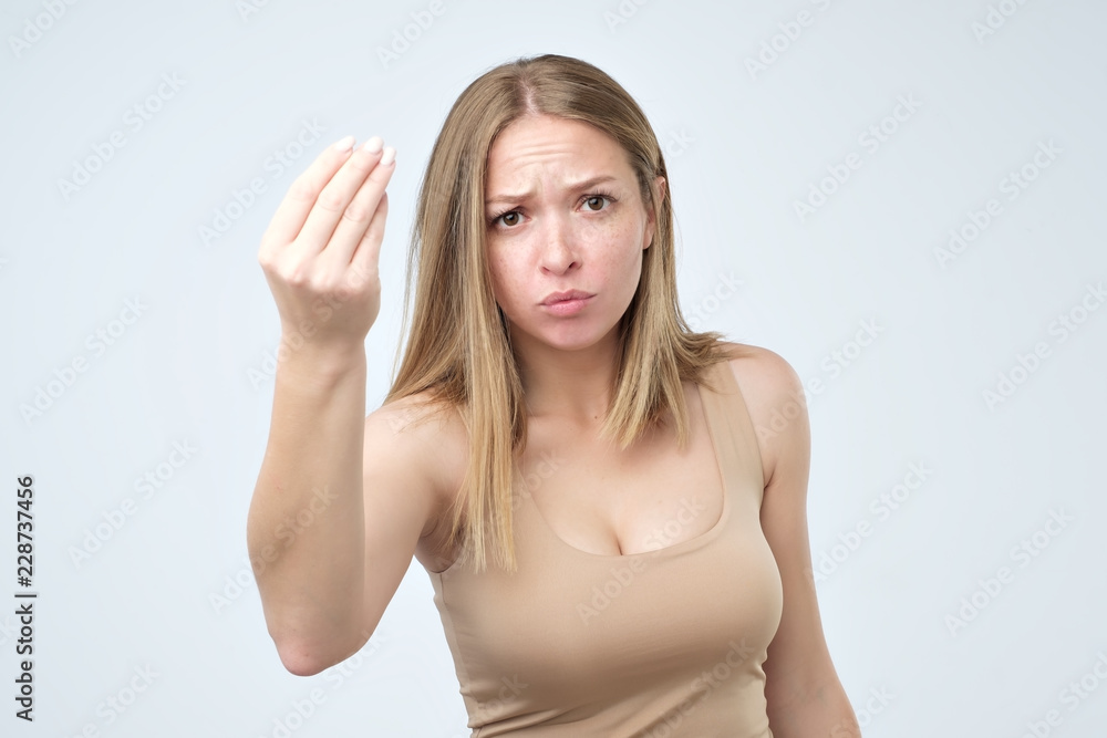 Portrait of young woman doing a typical italian gesture, frowning and looking straight ahead Portrait of young woman doing a typical italian gesture, frowning and looking straight ahead