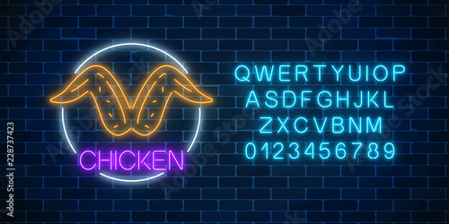 Neon glowing sign of chicken wings in circle frame with alphabet. Fastfood light billboard symbol.