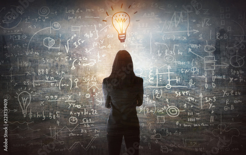 Young woman looking on the black board with mathematical formulas and calculations. Bright idea, way of thinking, discovery and challenge concept. 