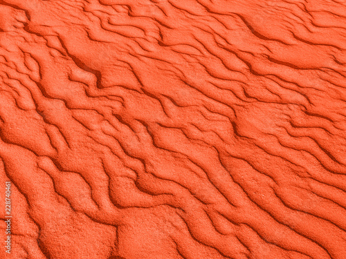 texture of red sand waves on the beach or in the desert. the ripples of the sand is diagonal.