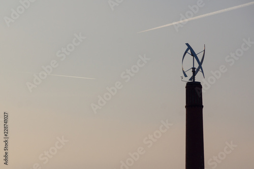 Vertical axis rotor wind generator on top of a large chimney  photo