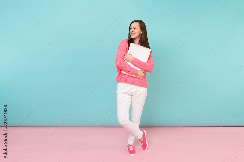 Full length portrait of woman in knitted rose sweater white pants holding laptop pc computer isolated on bright pink blue pastel wall background in studio. Fashion lifestyle concept Mock up copy space Full length portrait of woman in knitted rose sweater white pants holding laptop pc computer isolated on bright pink blue pastel wall background in studio. Fashion lifestyle concept Mock up copy space