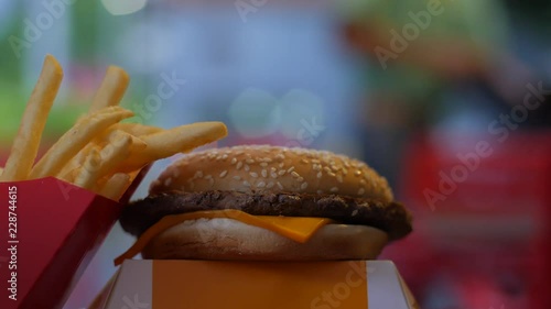 Hamburger and fried potatoes with blurred background of moving employee and car lights