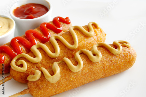 Corn dogs with ketchup and mustard on white background