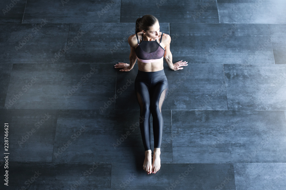 Athletic woman in a gym suit meditating on the floor top view with copy space for text.