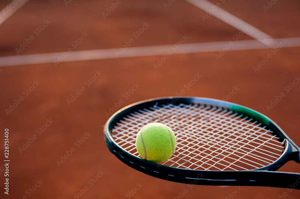 Ball and tennis racket on clay court.