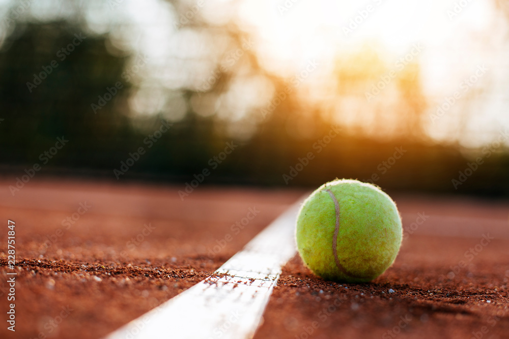 Tennis ball on clay court.	