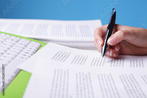Unrecognizable person reviewing a text (focus on pen and shallow depth of field)