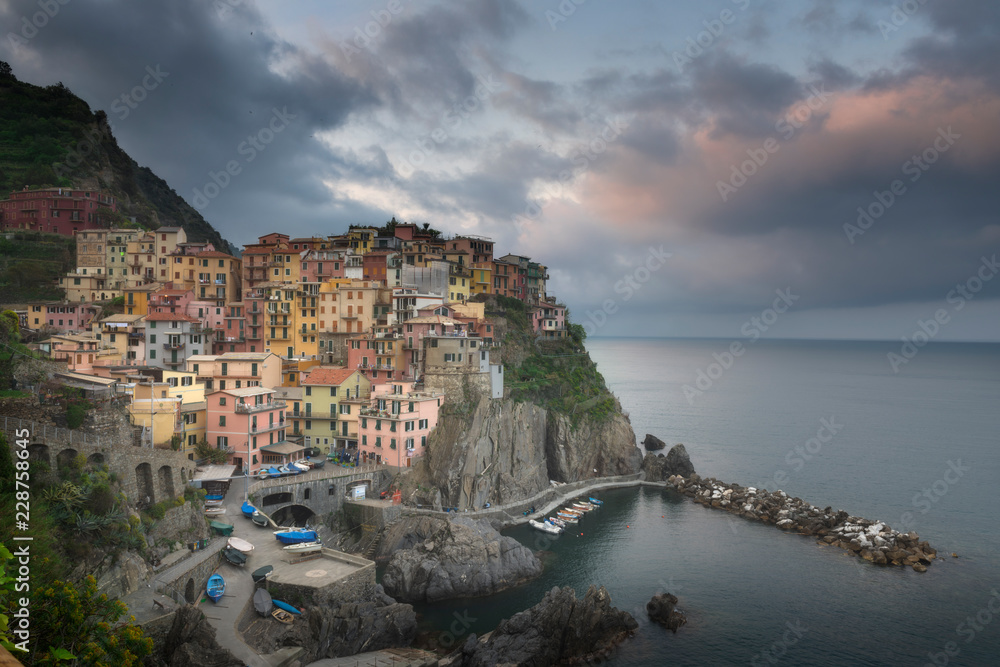 Second city of the Cique Terre sequence of hill cities - Manarola. Colorful spring sunset in Liguria, Italy, Europe. Picturesque seascape of Mediterranean sea. Traveling concept background