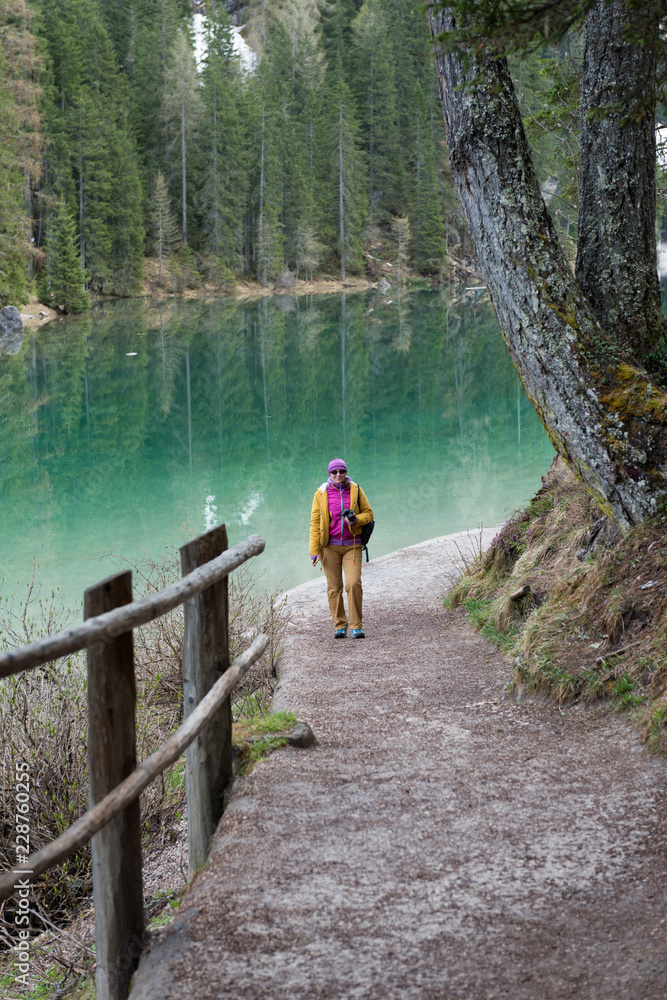 Woman walking around the Braies lake, Dolomites Italy