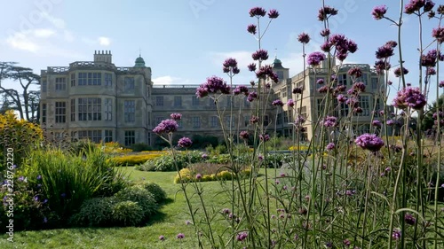 Breeze stirs tall purple flowers in the foreground of the garden Audley End mansion house in Saffron Walden, Essex, England