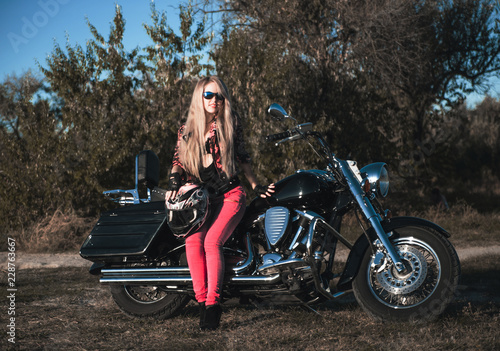 Biker blond woman outdoor with her motorcycle. 