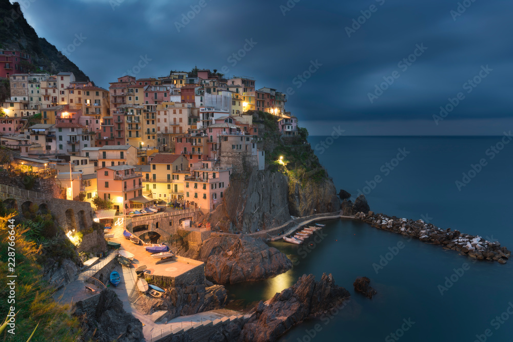Amazing view of Manarola city at evening light with costal rocks on a foreground. Cinque Terre National Park, Liguria, Italy, Europe.