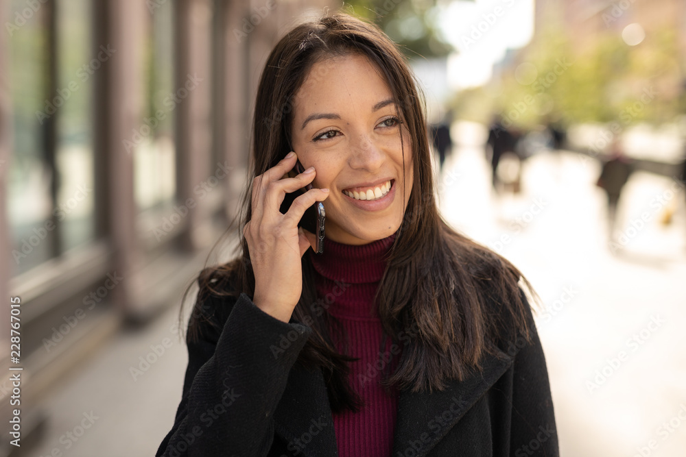 Young woman in city walking talking on cell phone Young woman in city walking talking on cell phone