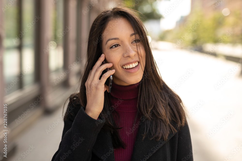 Young woman in city walking talking on cell phone Young woman in city walking talking on cell phone
