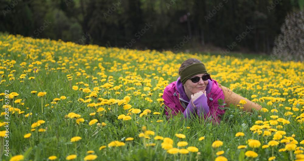 Active healthy woman having rest on beautiful meadow covered with flowers. Portrait of happy smiling young woman resting of mountains clearing during hike holidays Active healthy woman having rest on beautiful meadow covered with flowers. Portrait of happy smiling young woman resting of mountains clearing during hike holidays