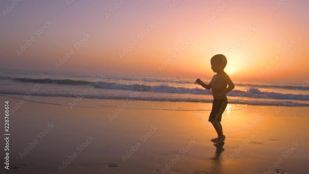Silhouette of child running and playing in the beach at sunset - freedom Silhouette of child running and playing in the beach at sunset - freedom