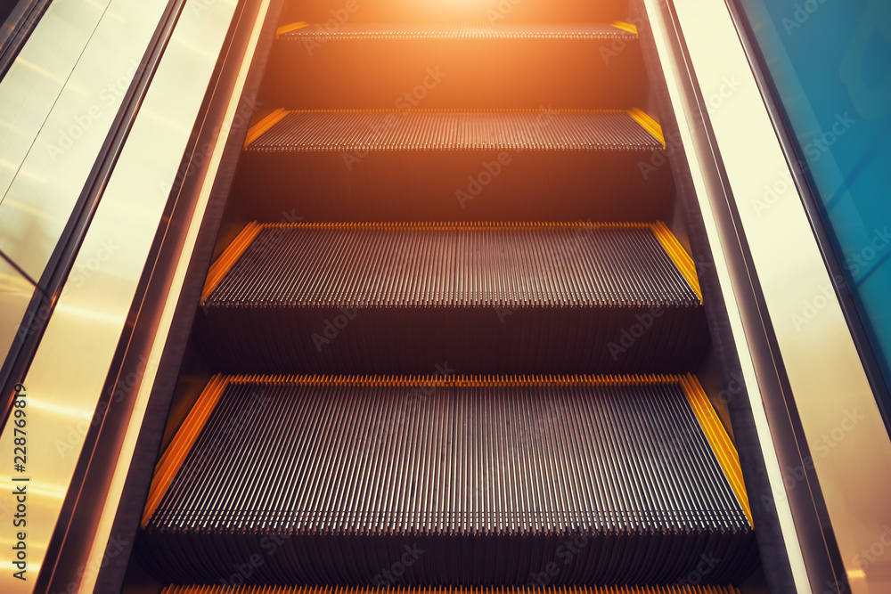 Obraz premium Empty escalator or moving stair. Also called stairway or staircase. Modern architecture design with step, glass for lift people up floor building i.e. shopping mall, airport, metro and subway station.