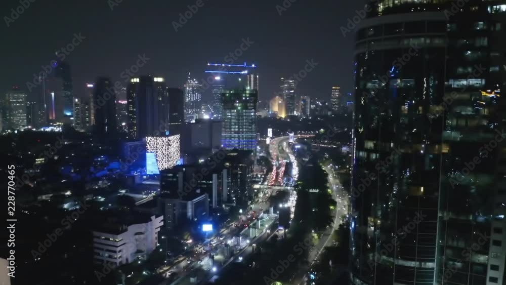 JAKARTA, Indonesia - October 15, 2018: Beautiful aerial view of modern office buildings with other skyscrapers and night traffic view in Jakarta downtown. Shot in 4k resolution