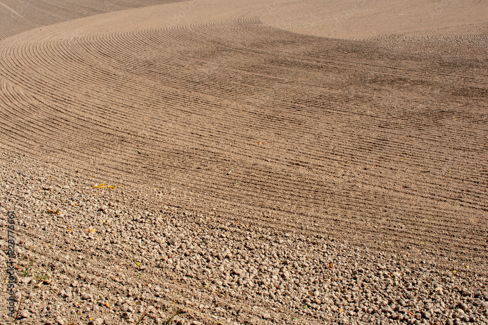 A close up view of newly tilled soil in a farm field prepared for planting, textures and patterns of till marks in swirls and patterns create an interesting background texture.