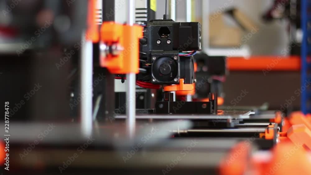 A collection of three 3D Printers shows them all printing, the camera racks focus from the middle printer to the closest one.