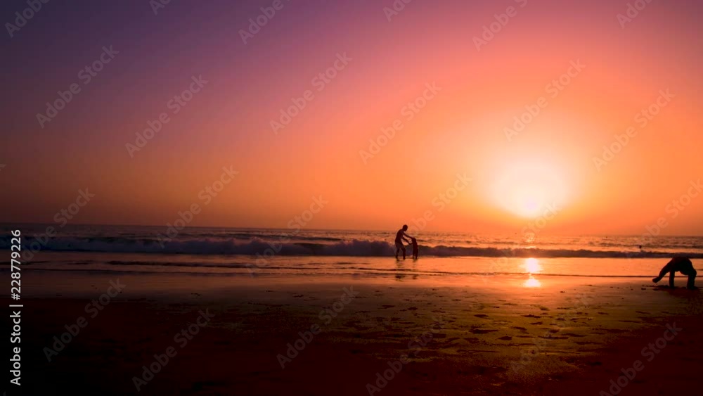 Silhouette of father playing with his son making him flying in the beach at sunset Silhouette of father playing with his son making him flying in the beach at sunset