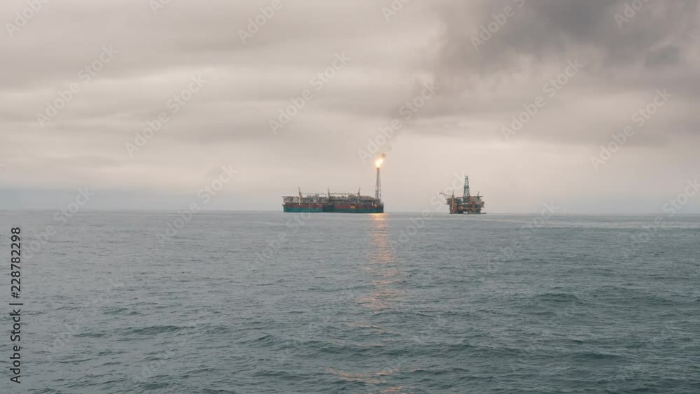 FPSO tanker vessel near Oil Rig platform. Offshore oil and gas industry. Flare is burning with smoke. Environmental pollution FPSO tanker vessel near Oil Rig platform. Offshore oil and gas industry. Flare is burning with smoke. Environmental pollution
